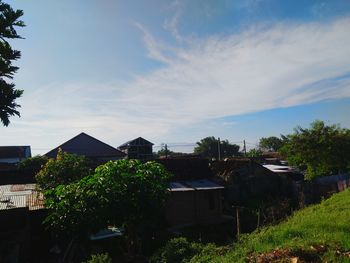 Houses by trees and buildings against sky