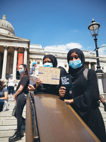 PEOPLE STANDING ON STREET AGAINST SKY