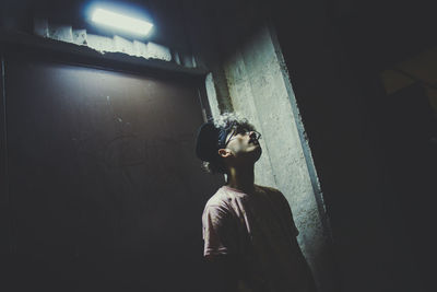 Close-up of man standing illuminated against wall at night