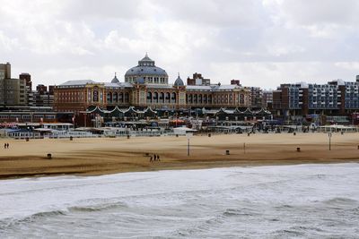 Park by sea against buildings in city against sky