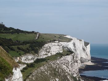 Scenic view of sea by cliff against sky