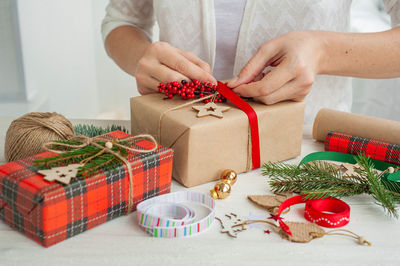 Decorating christmas presents. a woman decorates a box with a christmas gift spruce branch.