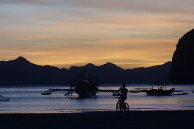 Silhouette boat in sea against sky during sunset