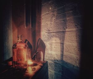 Close-up of illuminated lamp on table against wall