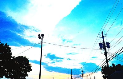 Low angle view of electricity pylon against blue sky