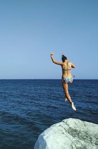 Rear view full length of woman wearing bikini jumping into sea