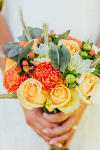 Midsection of bride holding bouquet