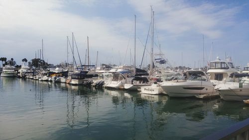 Boats moored at harbor against sky