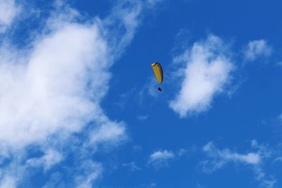 Low angle view of person paragliding against blue sky