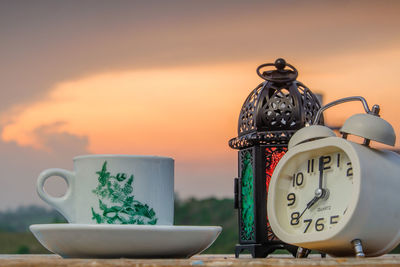 Close-up of clock on table at sunset