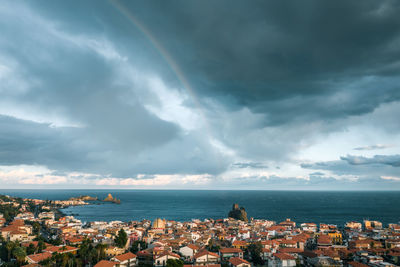 Aerial view of townscape by sea against sky