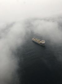 High angle view of ship sailing in sea under the clouds