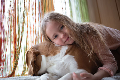Girl with dog sitting on bed at home