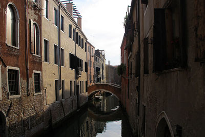 Arch bridge over canal amidst buildings in city