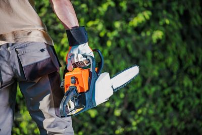 Midsection of man holding machinery