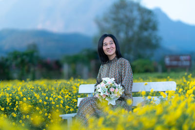 Portrait of woman with yellow flowers on field