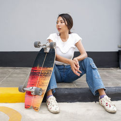 Full length of woman sitting against wall