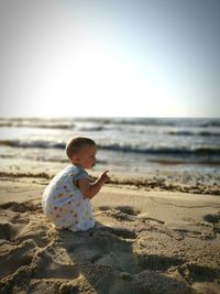 Baby boy on beach against clear sky