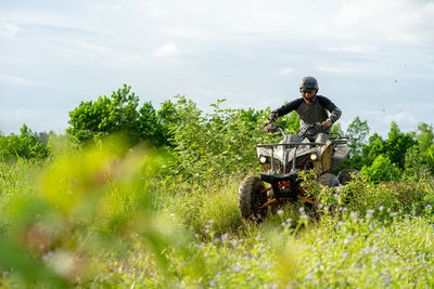 Man riding atv on plants against sky