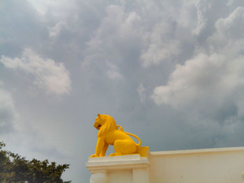 Low angle yellow of lion statue on building against sky