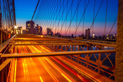 Light trails on bridge in city against sky