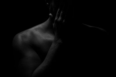 Midsection of shirtless man against black background