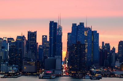 Illuminated buildings in city against sky during sunset