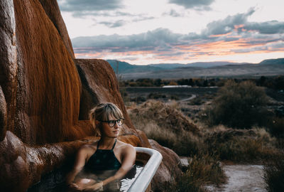 Portrait of beautiful woman on land against sky during sunset