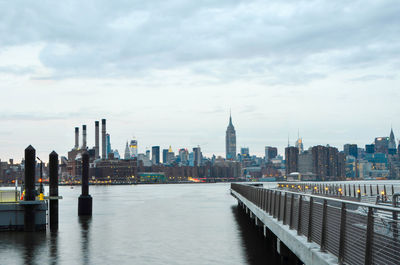 View of buildings at waterfront against cloudy sky