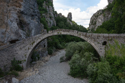 Ancient arch bridge over mountain against sky