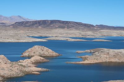 Scenic view of lake and mountains against clear blue sky