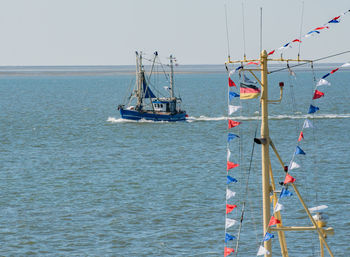 Fishing boats in sea against clear sky