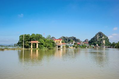 Scenic view of lake by building against blue sky