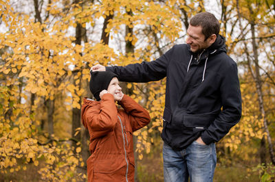 Dad plays with his son in warm clothes in the autumn forest