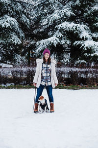 Portrait of smiling woman standing on snow covered field