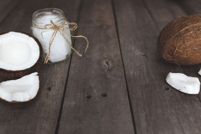 Broken coconuts on gray background with jar of raw organic extra virgin coconut oil. coconut pulp