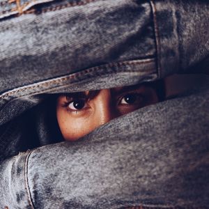 Close-up portrait of young woman looking through hands