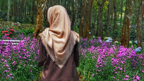 Woman standing by purple flowering plants in forest