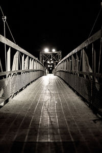 Surface level of illuminated footbridge against sky at night