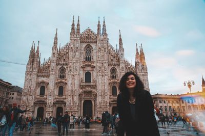 Portrait of smiling woman standing against church in city