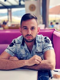 Portrait of young man sitting at table in restaurant