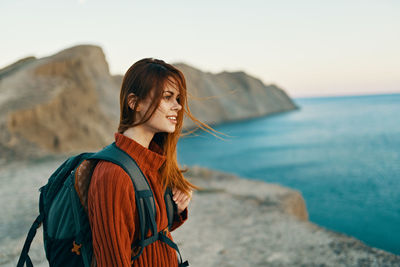 Portrait of young woman standing in sea against sky