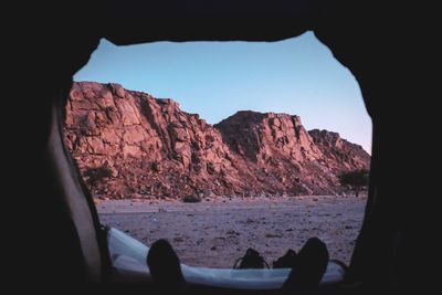 Rock formations by mountains against clear sky