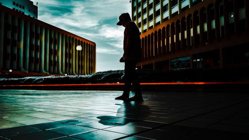 Man walking on road amidst buildings against sky