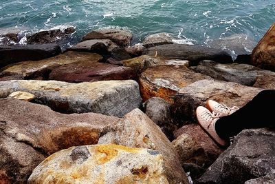 High angle view of hand on rock at sea