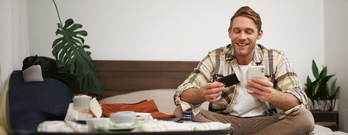 Portrait of senior woman using mobile phone while sitting on sofa at home