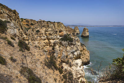 Rock formations by sea against clear sky