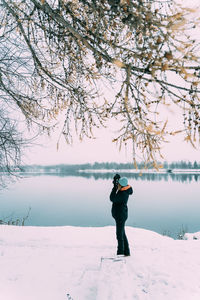 Full length of man photographing on lake during winter