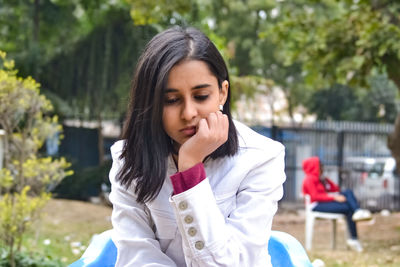 Thoughtful young woman sitting outdoors