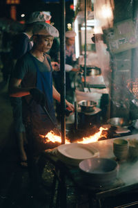 Side view of man preparing food at night